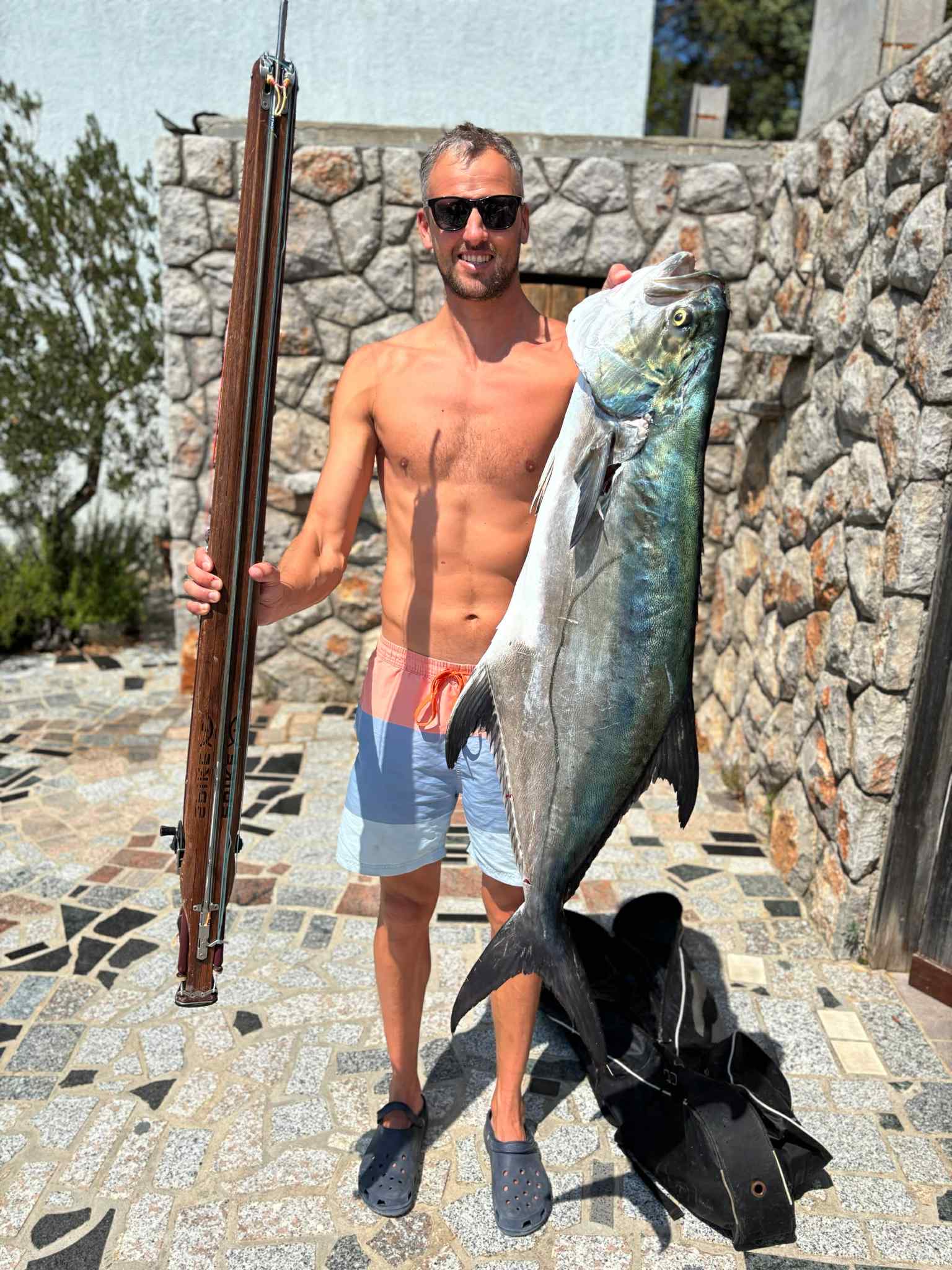 Man holding a large leerfish and a spike speargun.